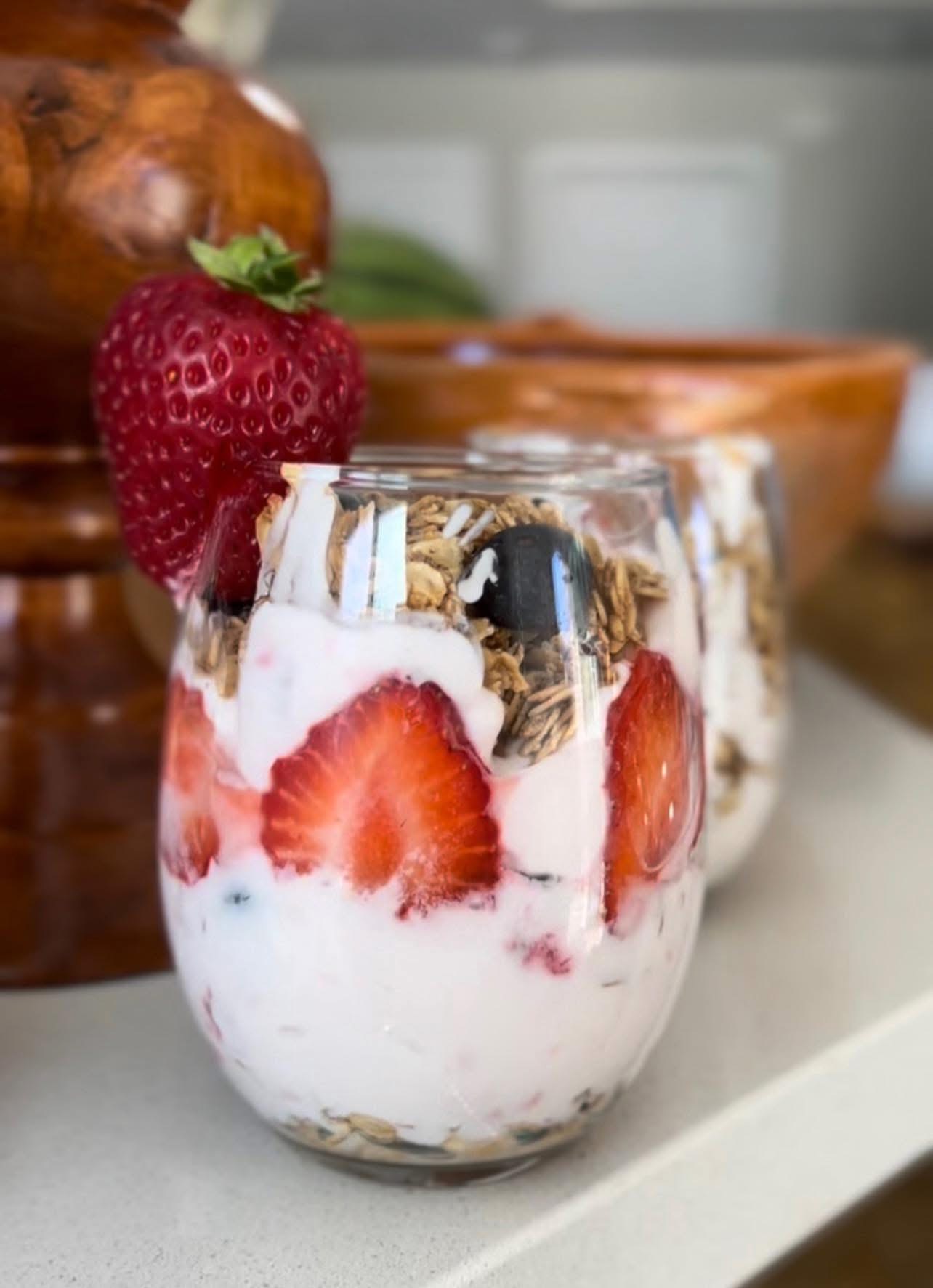Yogurt parfait glass layered with strawberries and Mishy & Sons granola